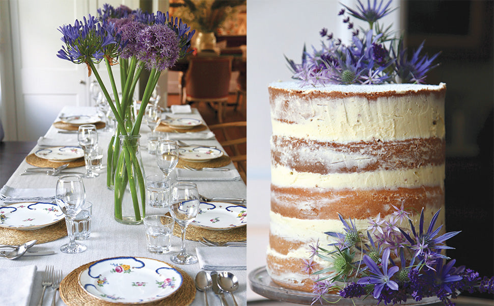 A neatly set dining table with floral plates and tall purple flowers, inspired by entertaining ideas from “An Entertaining Story” by Common Ground; beside it, a naked layered cake topped with purple blooms serves as picture-perfect party inspiration.