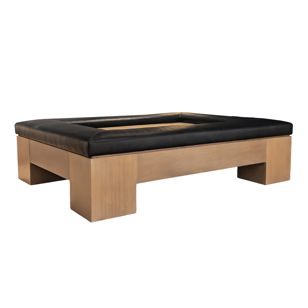 The Mikos Cocktail Ottoman by Hickory Chair features a large square wooden frame with substantial legs and a recessed center, accented by a sleek black cushioned border—an eye-catching, modern piece that seamlessly fuses contemporary style with refined sophistication.