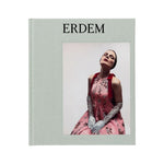 A hardcover book titled “Erdem” from Rizzoli features a cover image of a woman in a pink floral dress with lace gloves, posing with her head tilted back—an elegant tribute to the iconic style of British designer Erdem Moralioglu.