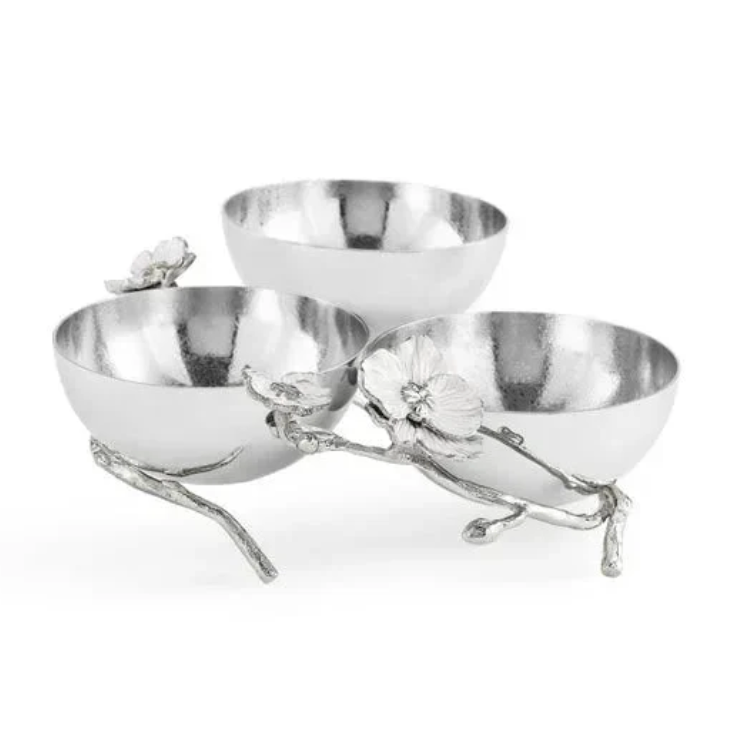 Three silver bowls from the Michael Aram Silver Orchid Collection are connected by a metal branch base adorned with floral accents, elegantly arranged in a triangular formation that evokes the purity and grace of an orchid plant.