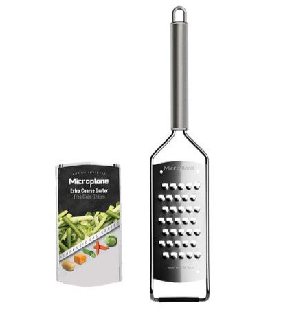 A Microplane Professional Series 2.0 extra coarse stainless steel grater with a black handle is displayed next to its packaging, which features vegetables and the product name.