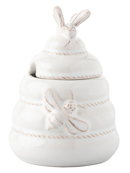 Juliska Clever Creatures Whitewash Honey Pot by Juliska adorned with bee designs and a bee-shaped handle on the lid, paired perfectly with a wooden spoon.