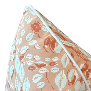 Close-up of the Cowrie Shell Coral Outdoor Pillow by Associated Design, featuring an orange and white seashell pattern with white piping—expertly crafted to elevate any space.