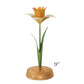 The Meadow Walk Daffodil Candle Holder Collection by Juliska features a 9-inch tall decorative flower sculpture with a green stem and leaves, yellow and orange petals, and a gold circular base.