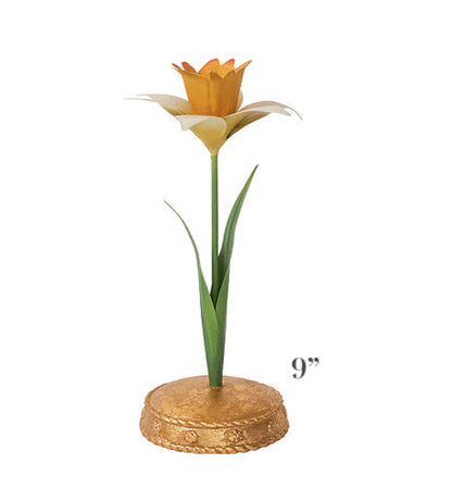 The Meadow Walk Daffodil Candle Holder Collection by Juliska features a 9-inch tall decorative flower sculpture with a green stem and leaves, yellow and orange petals, and a gold circular base.