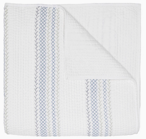 The Rimi Light Indigo Bedding by John Robshaw is a folded white, hand-quilted organic cotton quilt featuring vertical light blue and grey embroidery, with one corner turned over to reveal the underside.