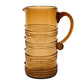 Inspired by Juliska’s Ella Drinkware Collection, this tall amber glass pitcher features a curved handle and elegant spiral ridges that wrap around the body, showcasing exquisite artisan mouth-blown glassware.