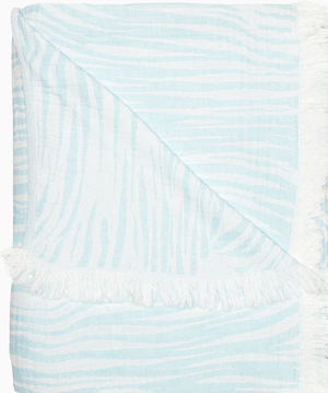 The John Robshaw Daasu Throw Collection features a soft, stonewashed cotton towel in light blue and white stripes with fringed edges.