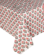 The SLOANE BY HAND Lily Table Linen Collection features a white tablecloth with a pink floral pattern and green stems, elegantly showcasing artisanal tableware for sophisticated settings.