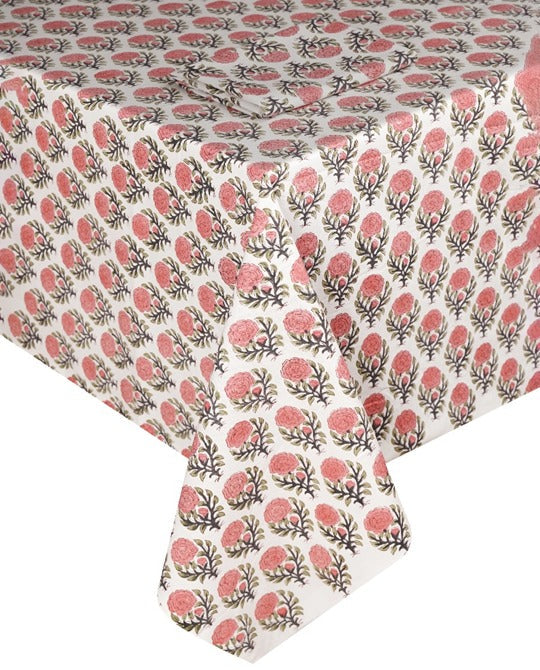 The SLOANE BY HAND Lily Table Linen Collection features a white tablecloth with a pink floral pattern and green stems, elegantly showcasing artisanal tableware for sophisticated settings.