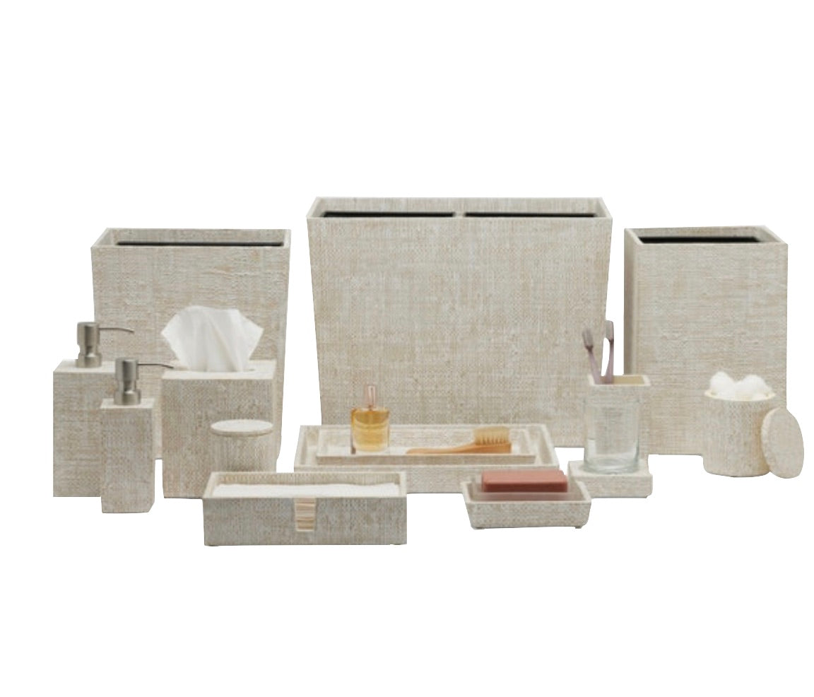 The Ghent Bath Collection by Pigeon & Poodle features beige bathroom accessories—woven grass tissue box, dispensers, trays, waste bins, toothbrush holder, soap dish, and cotton jar—shown beautifully on a white background.