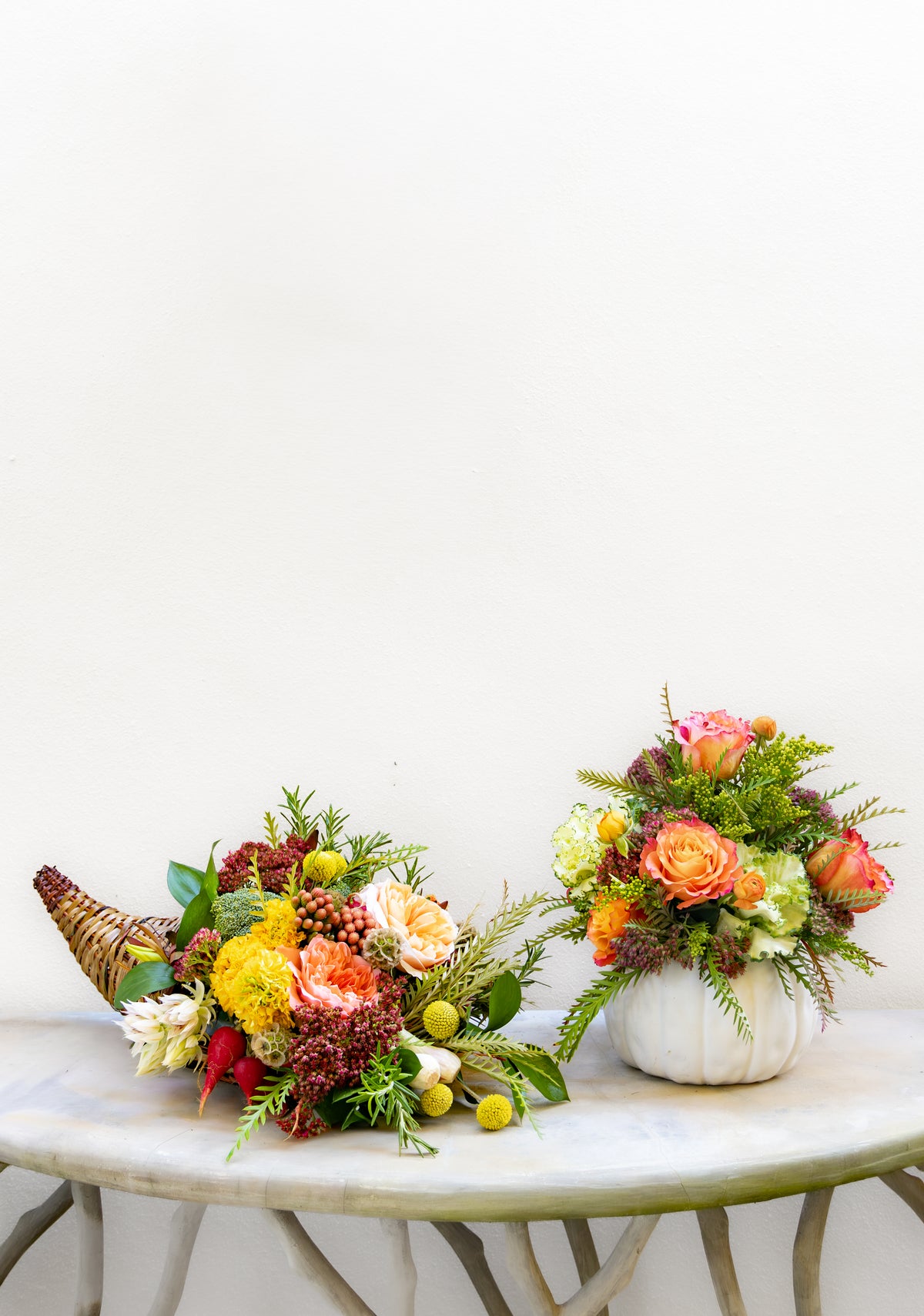 A floral cornucopia and a flower-filled white pumpkin vase sit on a pedestal table for a Hive Floral Class - Thanksgiving Class arrangement.