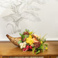 A Hive Floral Class - Thanksgiving Class centerpiece featuring a woven wicker cornucopia filled with yellow chrysanthemums, red radishes, and greenery on a wooden surface.