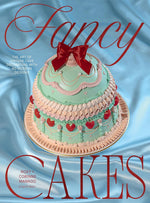 Fancy Cakes is a tiered, vintage-style cake with mint green and pale pink baroque buttercream, decorated with strawberries and a red bow on a blue satin background.