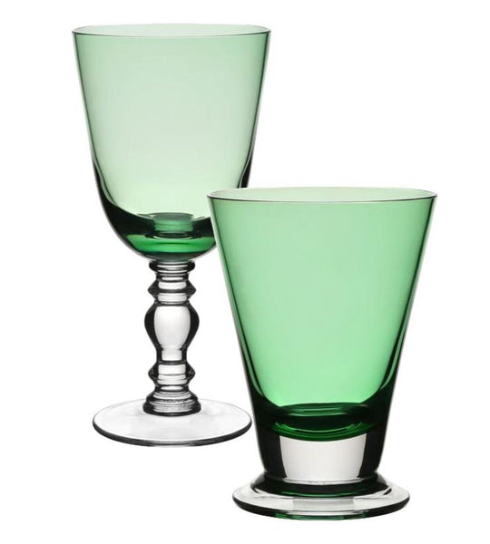 Two green glass goblets from the William Yeoward Crystal Apple Green Fanny Collection: one hand-blown with a stem and ornate base, and the other without a stem, resting on a wide circular base. Both feature a stunning Apple Green hue that captures the light beautifully.