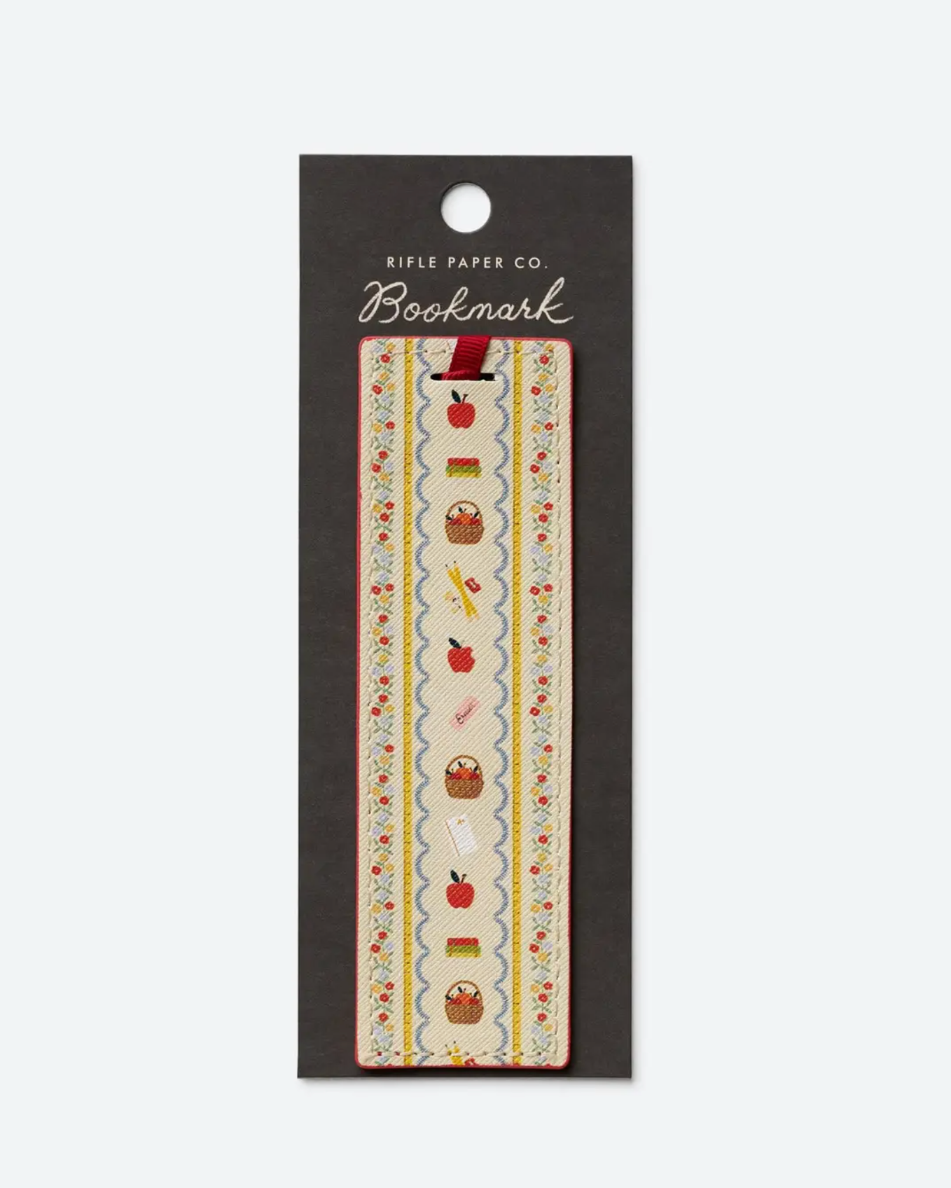 The Schoolhouse Collection rectangular embroidered bookmark from Rifle Paper Co. features charming motifs of apples, books, pencils, rulers, and cupcakes—perfect for adding schoolhouse style or gifting to teachers—and comes elegantly displayed on sleek black Rifle Paper Co. packaging.