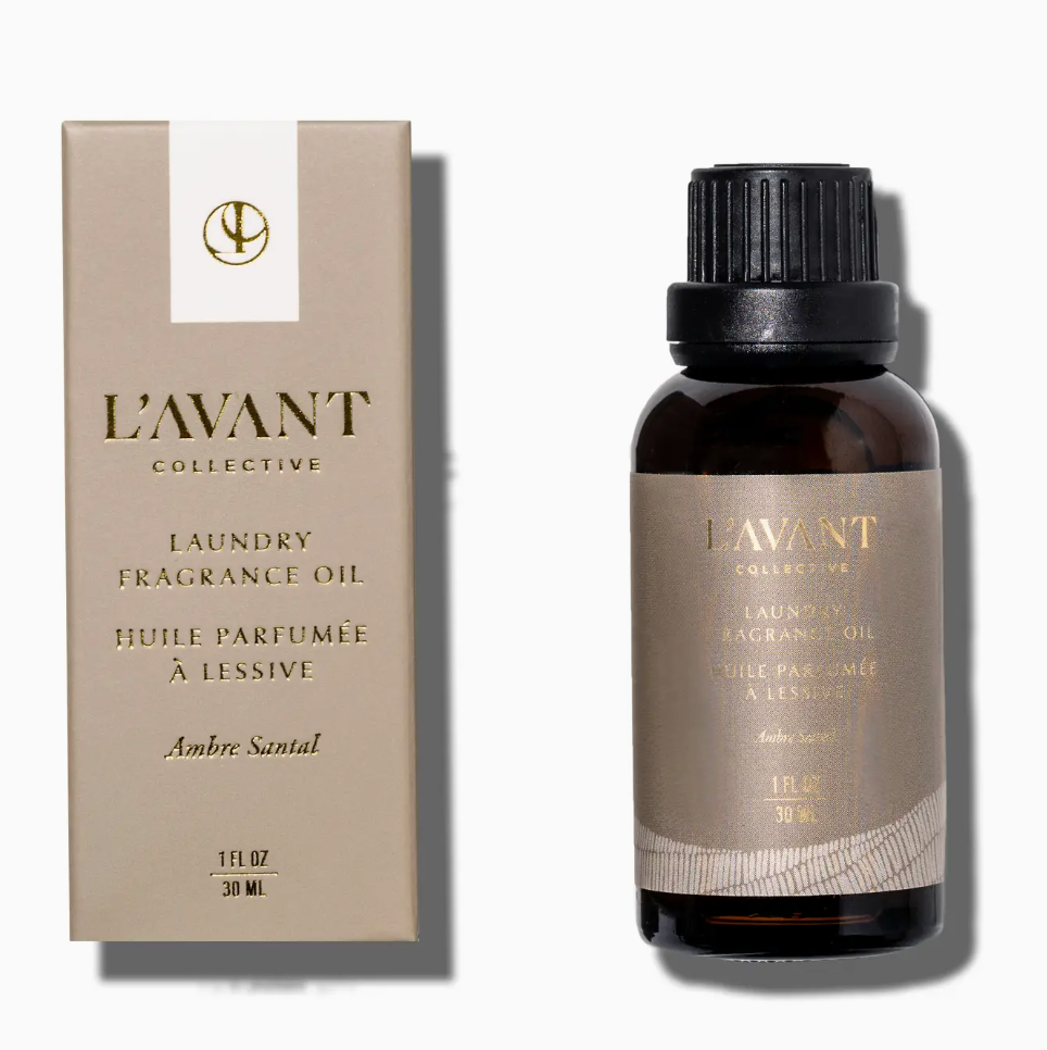 A box and a bottle of L’Avant Collective Ambre Santal Collection fragrance oil, both labeled with product details in English and French.