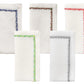 The Filament Napkin Set by Kim Seybert displays five white linen napkins, each with unique embroidered stitching—blue, red, green, black, and multicolored—shown against a white background.