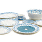 The Azure Blue Dinnerware Collection by Pink House Mustique features fine bone china plates, bowls, a mug, and a cup with saucer in blue geometric and floral patterns, elegantly arranged on a white surface.