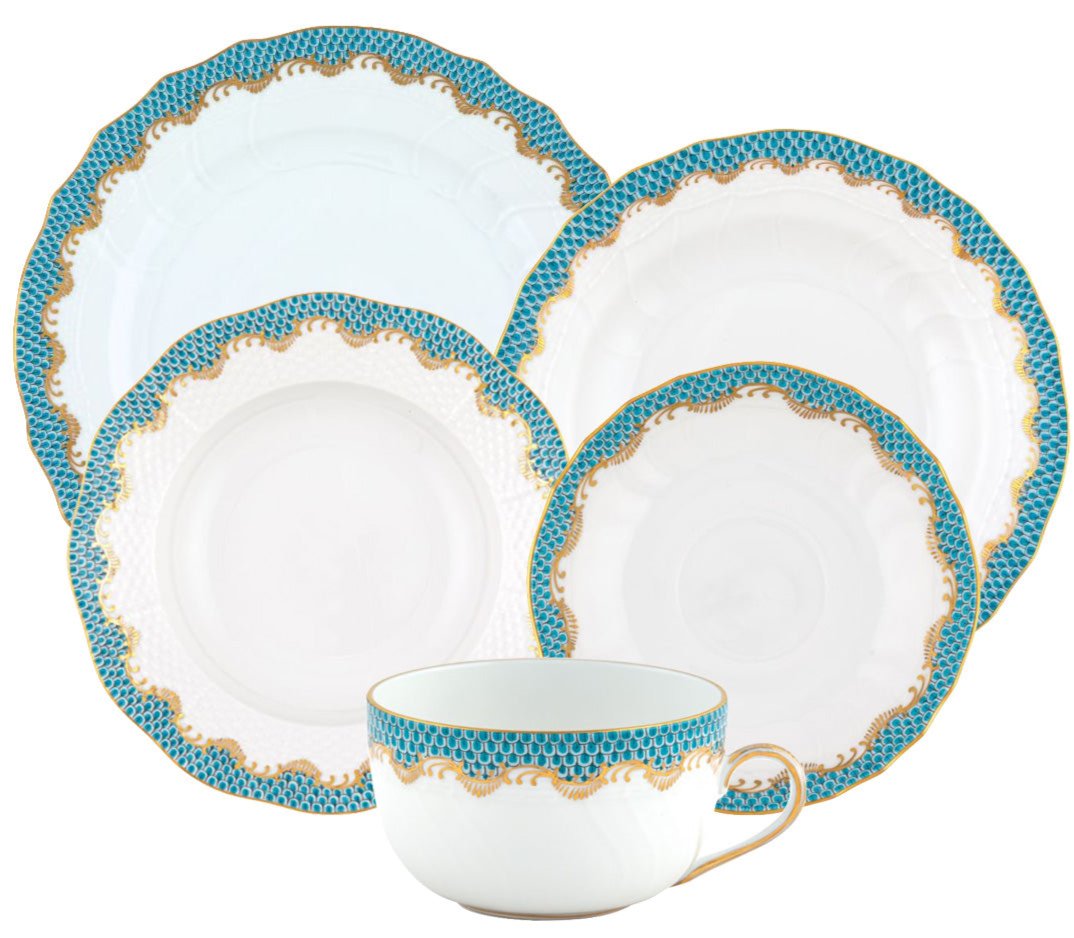 The Herend Fish Scale Turquoise Collection is a five-piece porcelain set featuring blue and gold patterned rims, four assorted plates, and a hand-painted matching teacup.