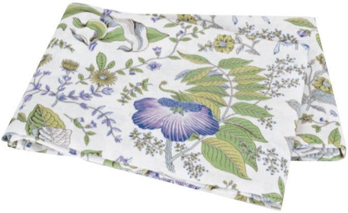 The Matouk Pomegranate Roman Linen Bedding Collection in Lilac features a folded white linen fabric with a floral pattern of green leaves and purple, blue, and yellow flowers.
