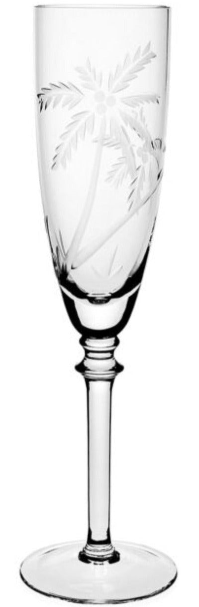 A clear glass champagne flute from the William Yeoward Crystal Palmyra Collection, featuring an etched design of palm trees on the bowl that evokes the pristine coral reefs of Palmyra Atoll.