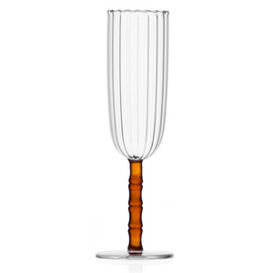 The Rivoli Drinkware and Tealight Collection by Ichendorf Milano features a clear, ribbed champagne flute with a bamboo-inspired amber stem and round base, displayed on a white background.