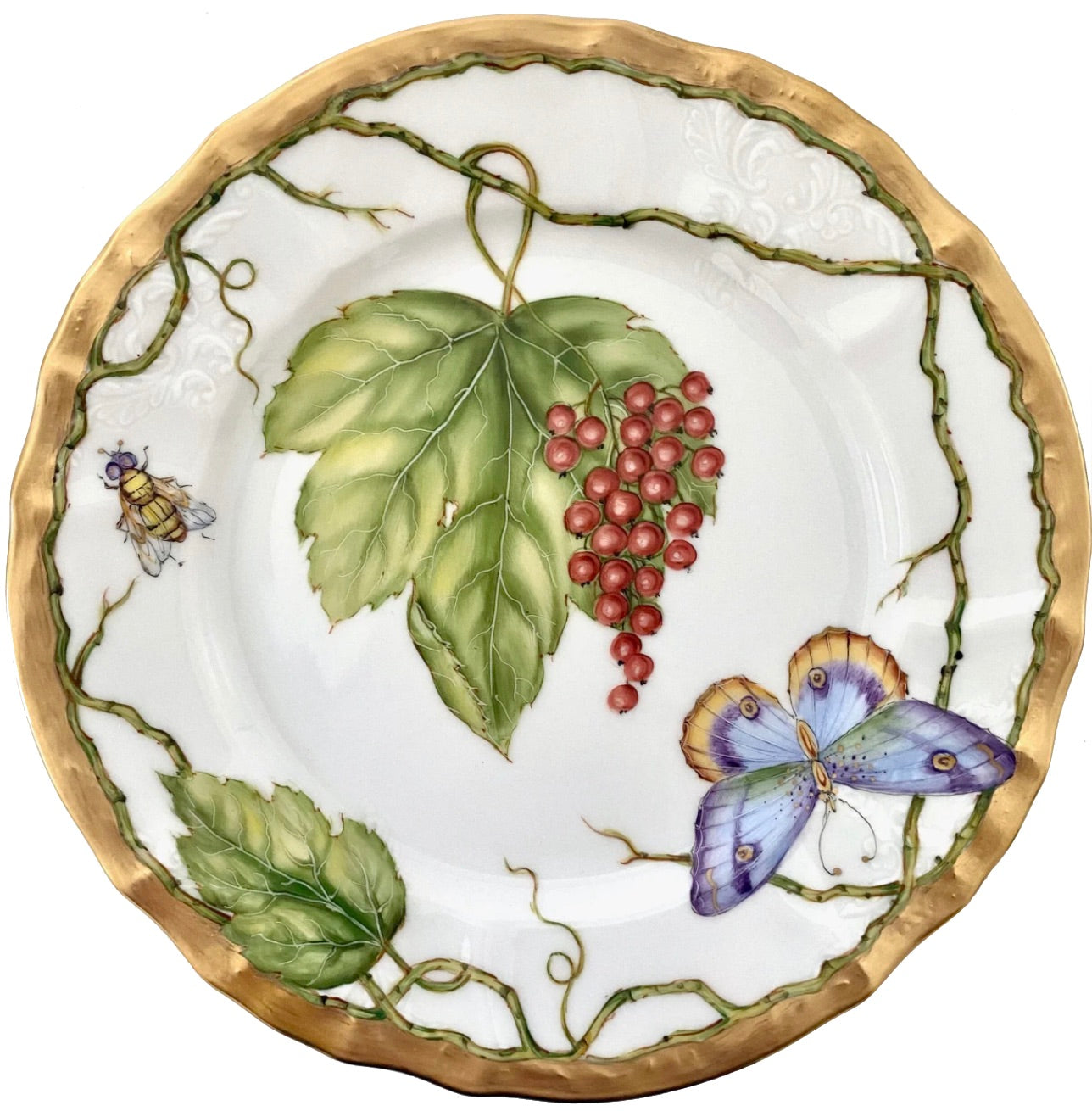 The Anna Weatherley Wildberries Salad Plate features hand-painted grape leaves, red berries, a blue butterfly, and a flying insect on white porcelain with a gold rim.