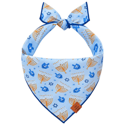Light blue triangular Festival of Lights Dog Bandana featuring a Hanukkah pattern of menorahs and dreidels.
