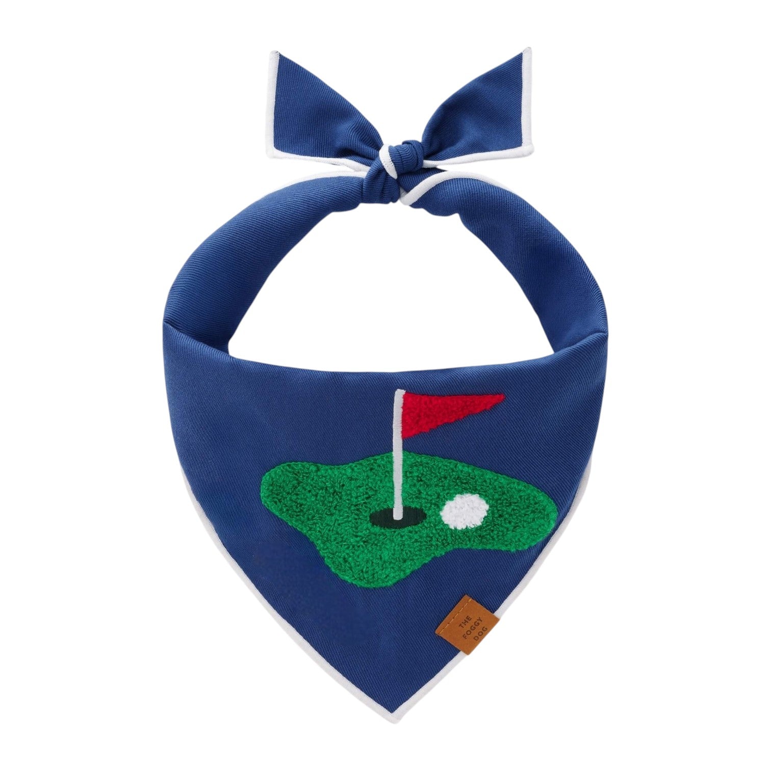 The Foggy Dog Golf Applique Dog Bandana features a golf green, hole, red flag, and ball embroidery with a knot top and brown tag—making it a unique golf accessory and perfect caddie gift.