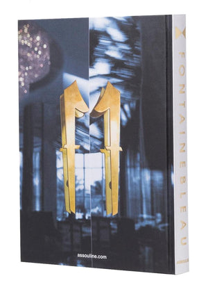 The Assouline book "Fontainebleau" features a gold geometric cover design inspired by architectural marvels. The title is displayed vertically on the spine, echoing its luxurious namesake hotel, and includes the publisher's website elegantly at the bottom.