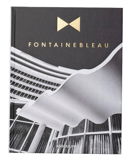 The Assouline book "Fontainebleau" features a black-and-white cover image of architectural beauty, adorned with gold lettering. It exudes luxury, reflecting the grandeur reminiscent of the iconic Fontainebleau hotel.
