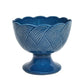 Juliska’s Le Panier Mystic Knot Denim Pedestal Bowl features a scalloped rim and a textured, woven pattern inspired by the mystic knot motif around the body.