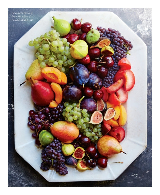 A white platter overflowing with an assortment of fresh fruits—such as grapes, figs, cherries, pears, plums, and apricots—artfully arranged in a vibrant, tapas-style grazing presentation inspired by Graze from Penguin Random House.