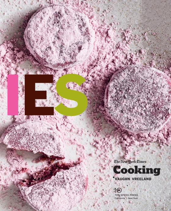 Four round Cookies from Penguin Random House, dusted in pink powdered sugar—with one cookie broken open—sit atop a white surface dusted with more pink powder. Bold, colorful letters spelling “IES” overlay the image, capturing the playful spirit of Cookies you’d expect from a Penguin Random House dessert collection.