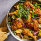 Enjoy a delicious pan of cooked chicken legs with green beans, purple onions, lime wedges, and fresh cilantro garnish—all featured in Dinner Tonight by Penguin Random House. Perfect for easy cleanup and ideal for stress-free weeknight dinners.