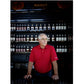 A man in a red polo shirt stands before shelves lined with bottles. Text below reads: “EDDIE RUSSELL, Master Distiller, Wild Turkey,” showcasing his deep expertise as featured in “Bourbon, The Story of Kentucky Whiskey” from Penguin Random House.