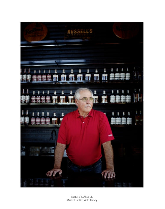 A man in a red polo shirt stands before shelves lined with bottles. Text below reads: “EDDIE RUSSELL, Master Distiller, Wild Turkey,” showcasing his deep expertise as featured in “Bourbon, The Story of Kentucky Whiskey” from Penguin Random House.