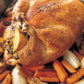 A whole roasted chicken with golden-brown skin, inspired by Barefoot Contessa At Home from Penguin Random House, stuffed with lemon and herbs and nestled on a bed of roasted carrots and onions in a baking pan—a classic East Hampton dinner.