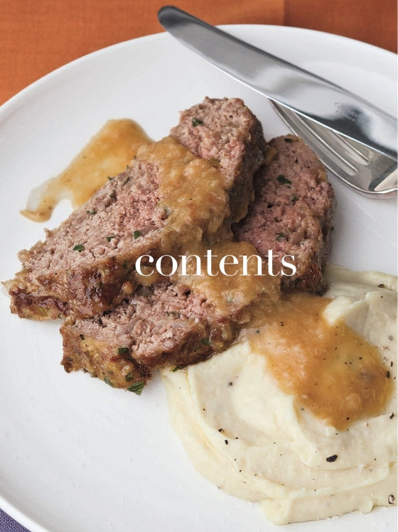 Two slices of meatloaf with brown gravy and a serving of mashed potatoes are arranged on a white plate beside a metal knife. Evocative of the cozy, rich flavors featured in Barefoot Contessa Foolproof by Penguin Random House, this inviting dish promises a satisfying meal. The word “contents” is overlaid on the image.