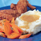 A comforting blue plate featuring fried chicken, mashed potatoes with savory gravy, and dill-garnished sliced carrots—perfectly capturing the inviting spirit of home-cooked meals celebrated in Barefoot Contessa Family Style from Penguin Random House.