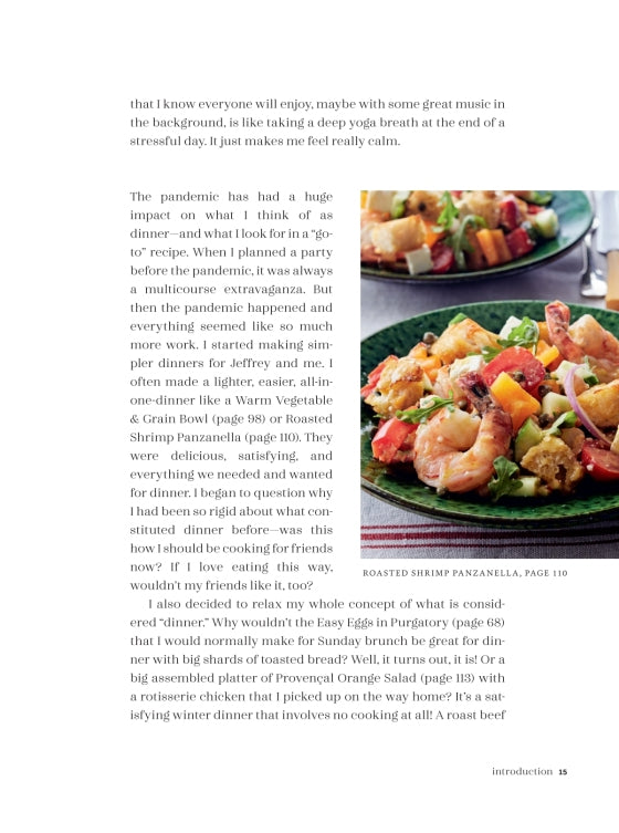 A cookbook page from Go-to Dinners by Penguin Random House features text about meal planning during the pandemic and a photo of a salad with shrimp, vegetables, and greens on a white plate. Inspired by Ina Garten recipes, the content provides easy dinner ideas and comforting recipes designed to help navigate uncertain times.