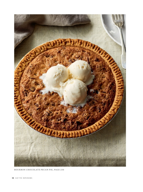 A whole pecan pie topped with three scoops of vanilla ice cream sits on a beige tablecloth next to a plate and spoon, making it the perfect sweet finish to any recipe from Go-to Dinners by Penguin Random House.