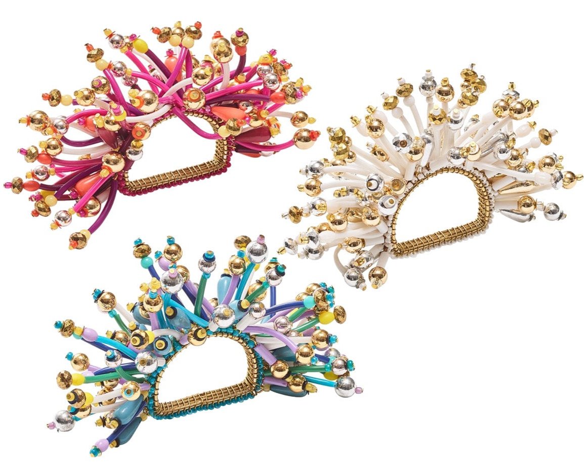 The Kim Seybert Fun Burst Napkin Ring features metallic beads and flexible, curled silicone tubes in pink, white, and blue for a colorful tabletop accent.