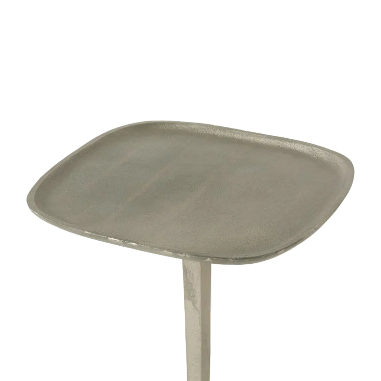 A close-up of the Made Goods Brenna Drinks Table in antique silver—a stylish, square metallic table with slightly curved edges, tray top design, and single central leg.