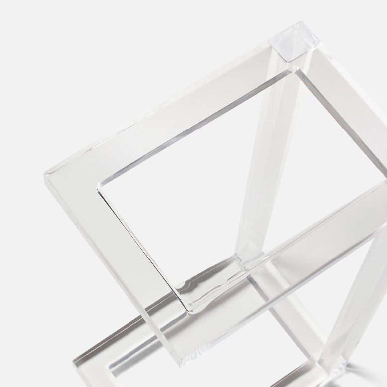 The Clark Acrylic Accent Table by Made Goods features intersecting rectangular frames in clear acrylic, creating a chic geometric sculpture perfect as an accent piece against a white background.