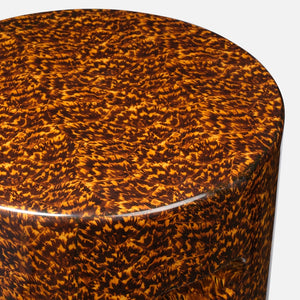 Close-up of the Elton Stool by Made Goods, featuring a cylindrical shape with a high-gloss finish and a mottled faux tortoise shell pattern in brown, orange, and black tones.