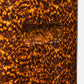 Close-up of the Elton Stool by Made Goods, featuring a textured brown and orange faux tortoise shell pattern with a smooth, curved center indentation.