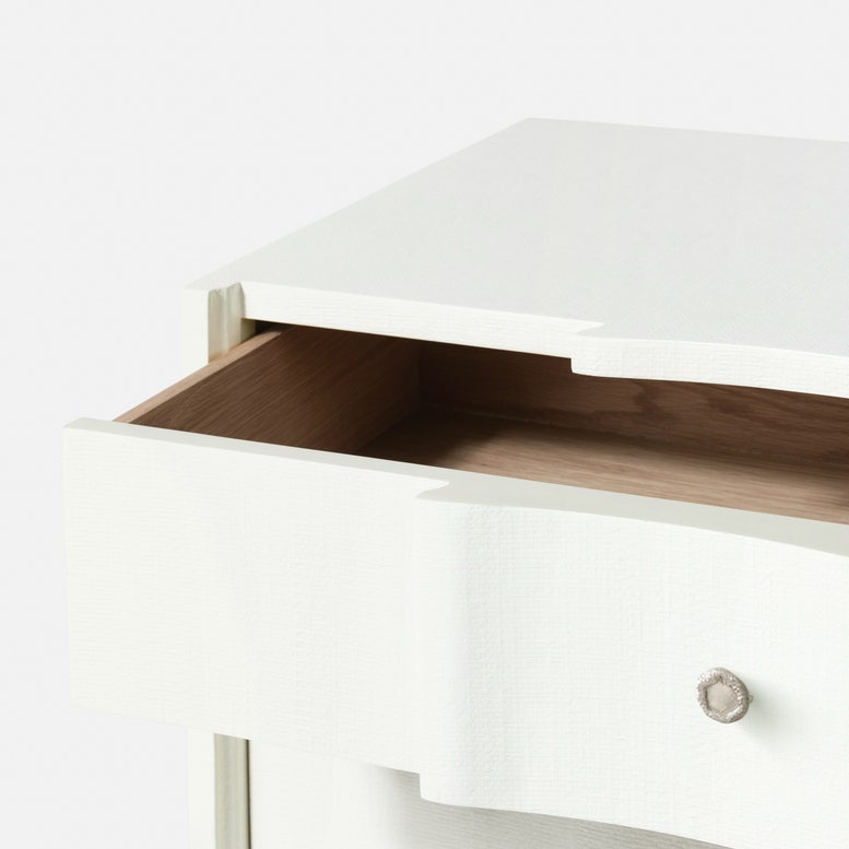 The Essery Dresser Collection by Made Goods features a white wooden nightstand with a single soft-close drawer, showcasing a light wood interior and a textured faux raffia finish.