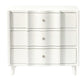 A white wooden nightstand from the Made Goods Essery Nightstand Collection features four drawers with vertical wave details, round knobs, faux raffia accents, and short tapered legs—a transitional piece for any room.